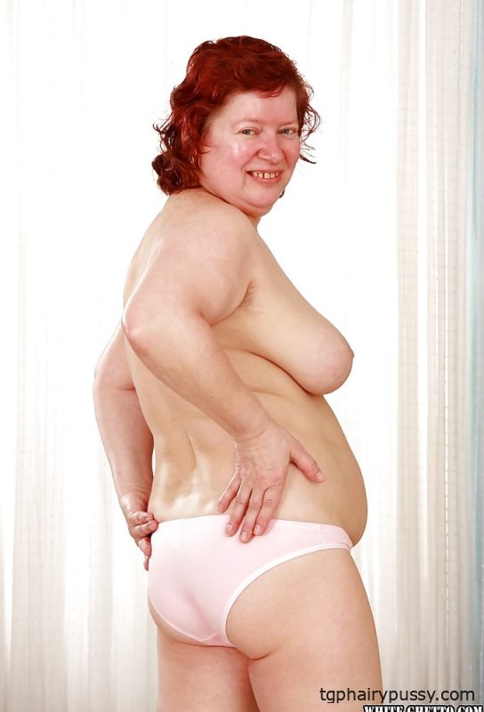 Толстая рыжая бабушка с массивными кувшинами снимает с себя одежду