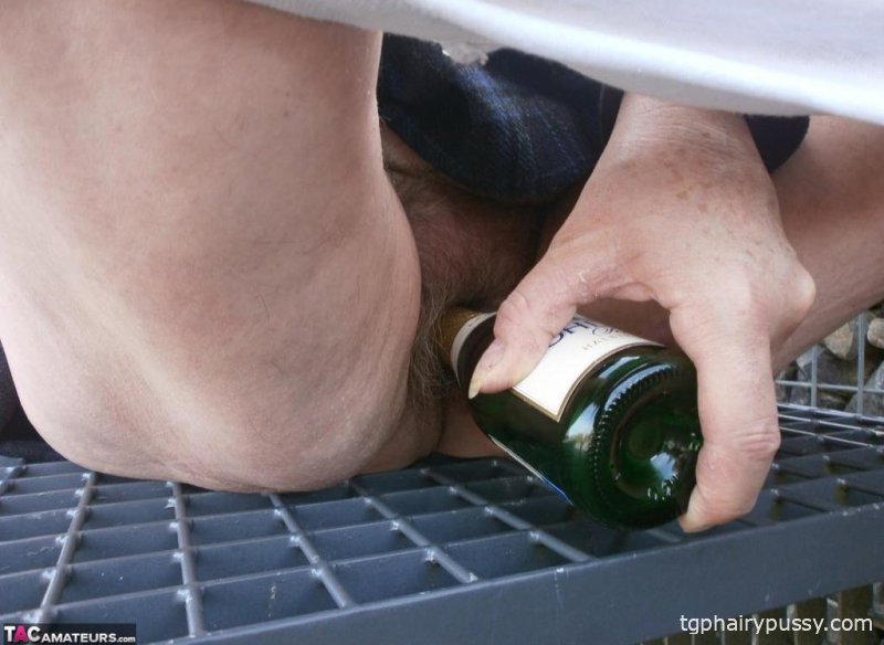 Возбужденная старая Каро на улице в сапогах раздвигает киску, чтобы поиграть с бутылкой вина